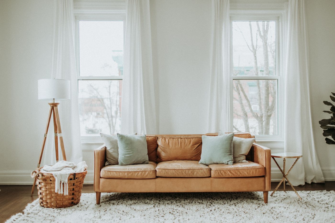 A sunlit room with a tan sofa and white curtains